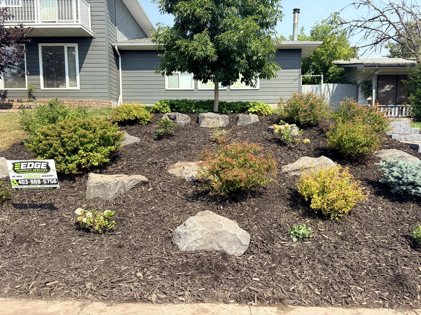 Same bed cleared, mulched and boulder-set by Edge Property Services