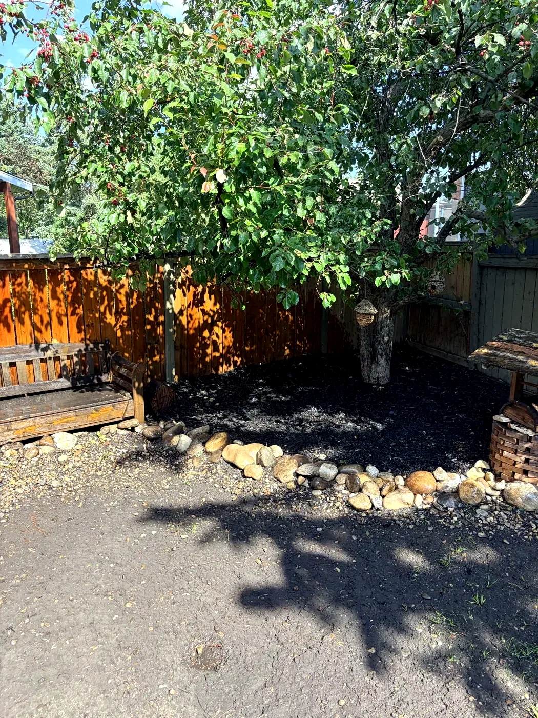 Same corner cleaned, re-edged with river rock and fresh black mulch by Edge Property Services