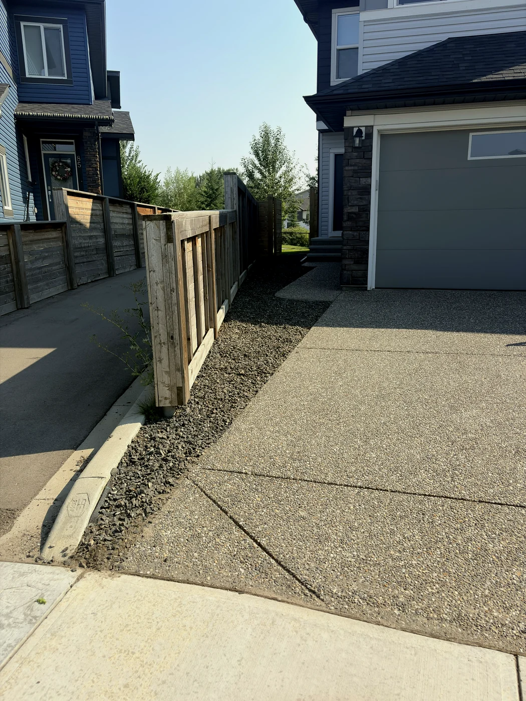 Rock strip along the fence weeded clean from curb to gate by Edge Property Services — Calgary