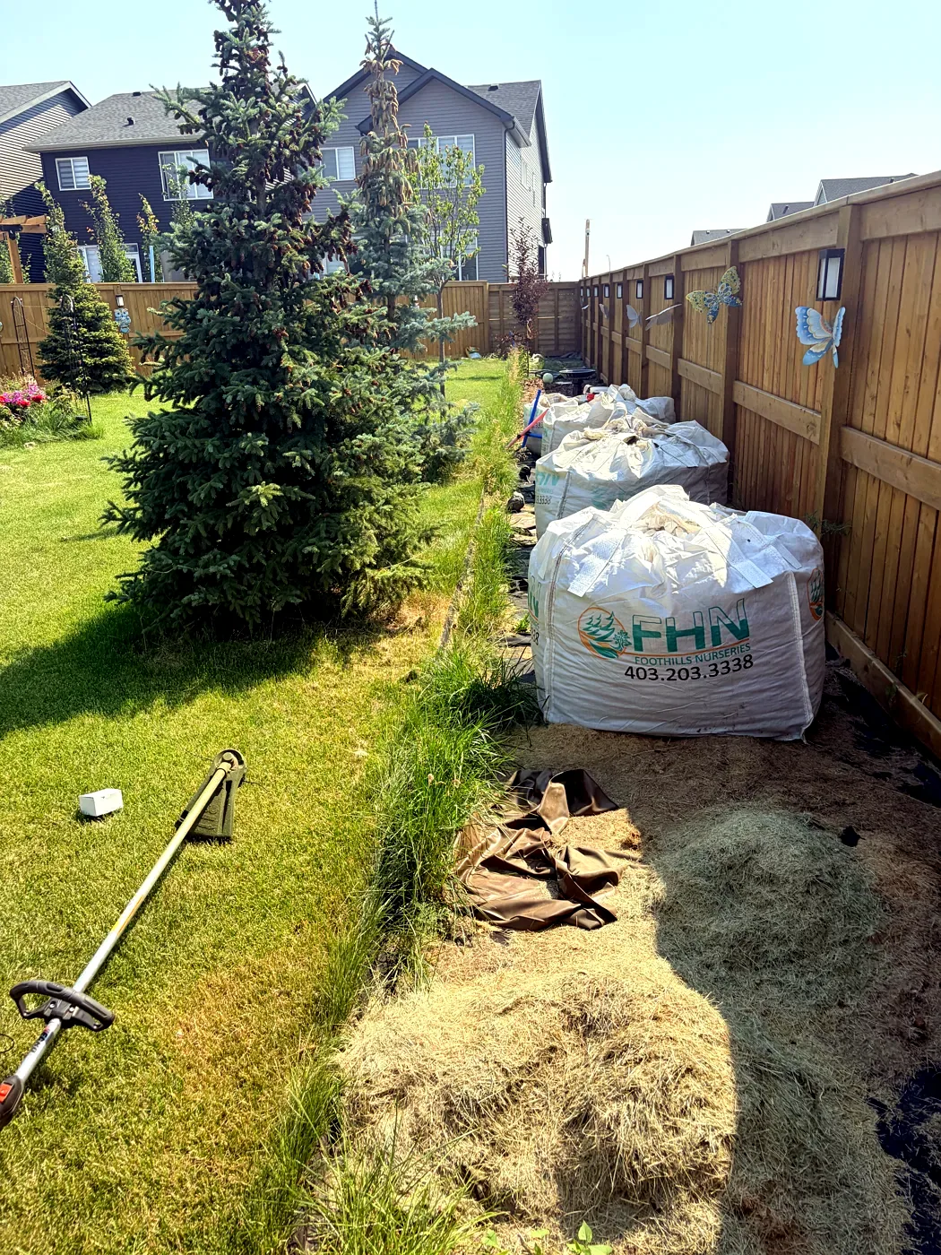 Fence line before new garden bed installation — Calgary