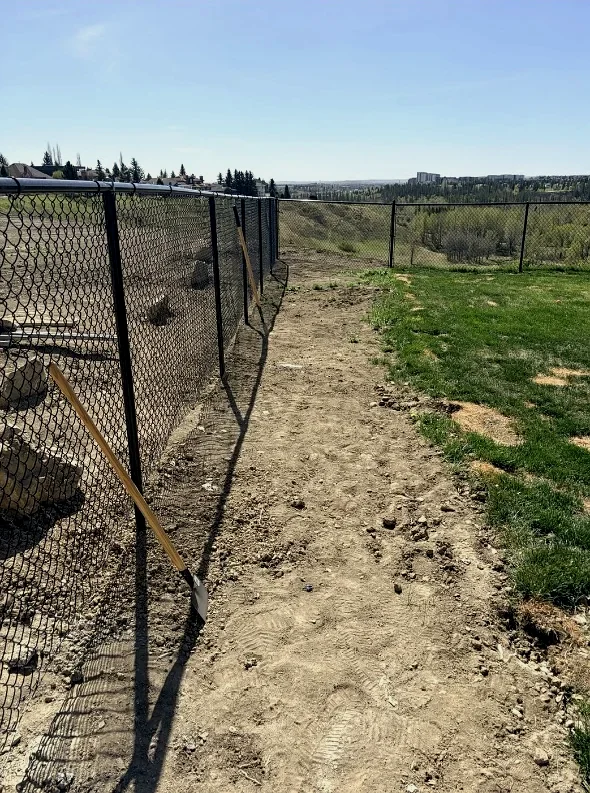 Torn-up fence line with bare dirt on a Calgary ridge; before landscaping
