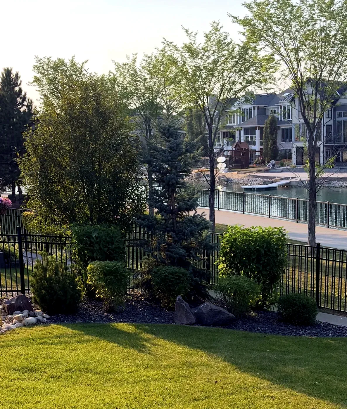 Sculpted bushes and shrubs shaped along a Calgary lakefront yard by Edge Property Services
