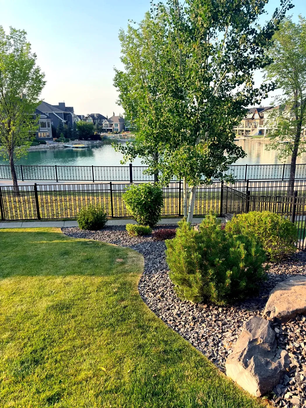 Manicured lakefront yard with curved lawn edge and slate rock beds — Calgary lake community
