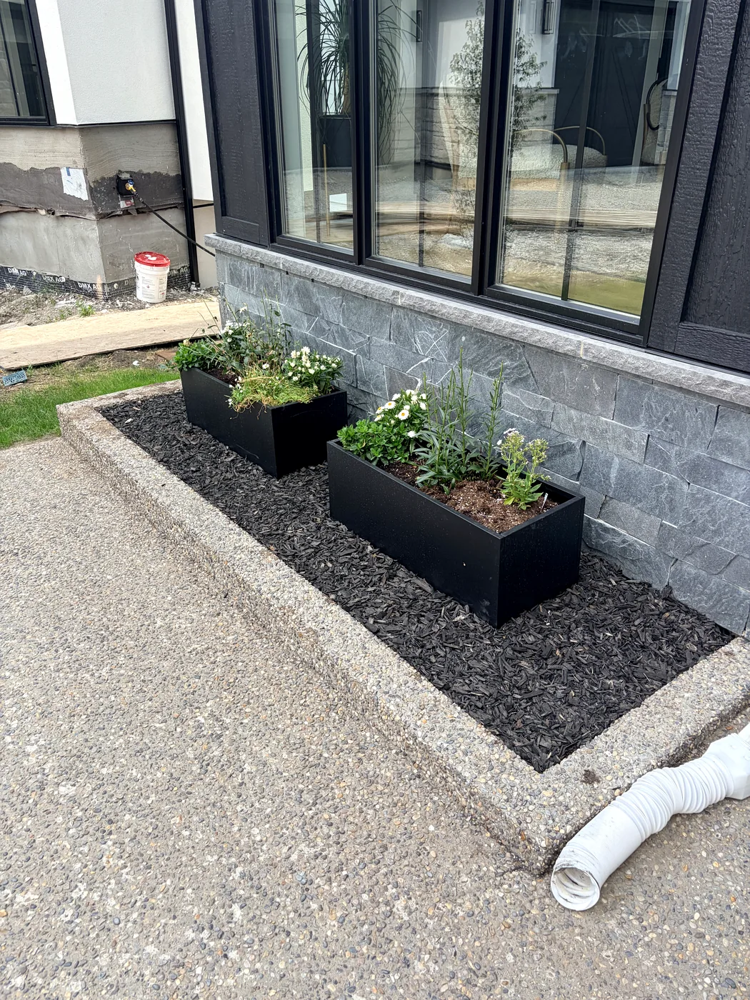 Black mulch bed with modern planters at a Calgary home — installed by Edge Property Services