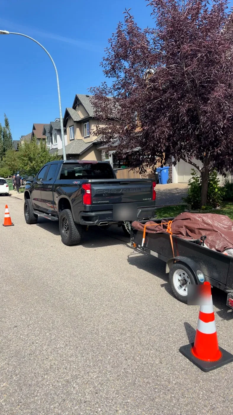 Edge Property Services truck and loaded hauling trailer on a Calgary street — junk removal in progress